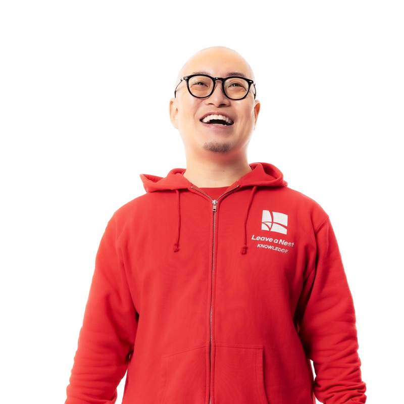 Takeshi Hiratsuka laughing, wearing a red Leave a Nest hoodie